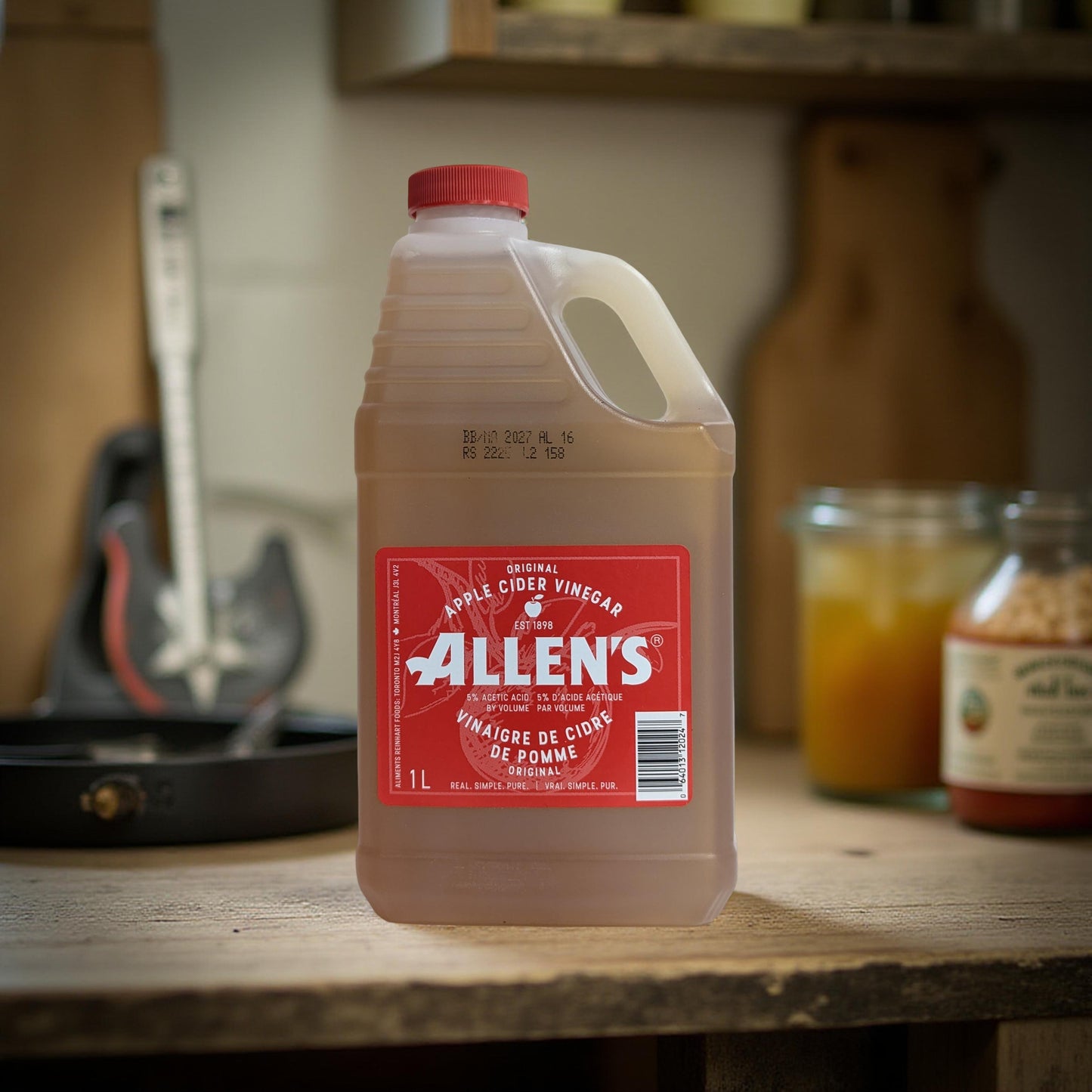 Bottle of Allen's Apple Cider Vinegar on a wooden surface with kitchen items in the background