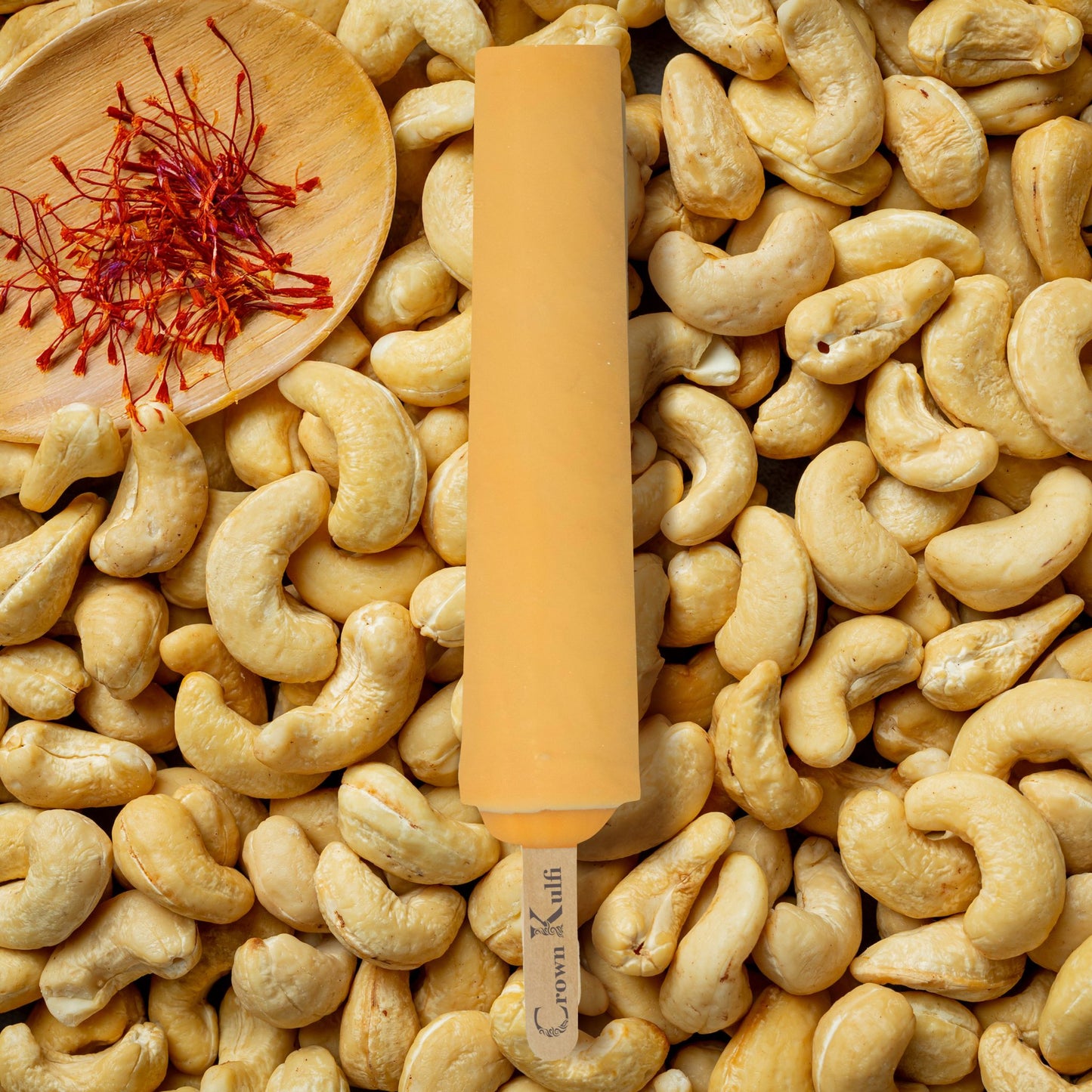 Cashew nut with a stick on a bed of cashews, accompanied by saffron strands.