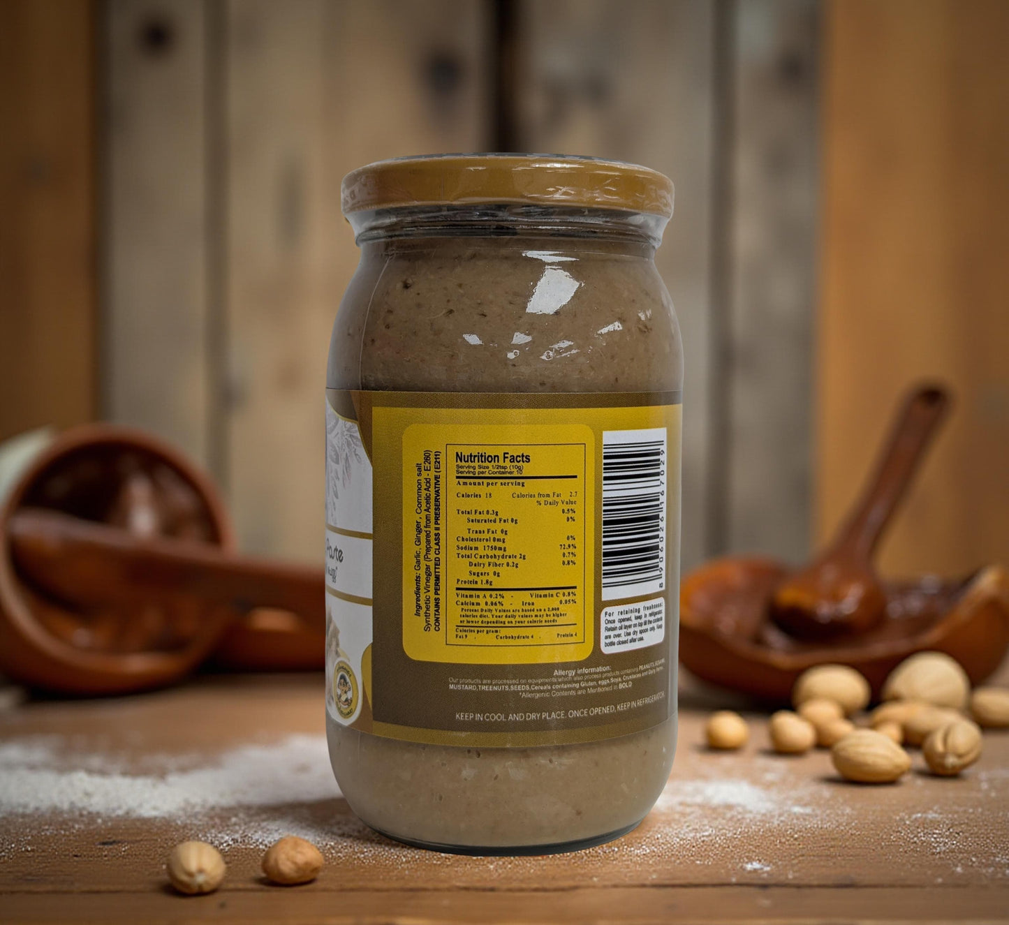 Jar of nutella with a wooden spoon and hazelnuts on a wooden surface