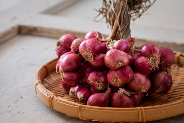 Bunch of red onions on a woven bamboo tray