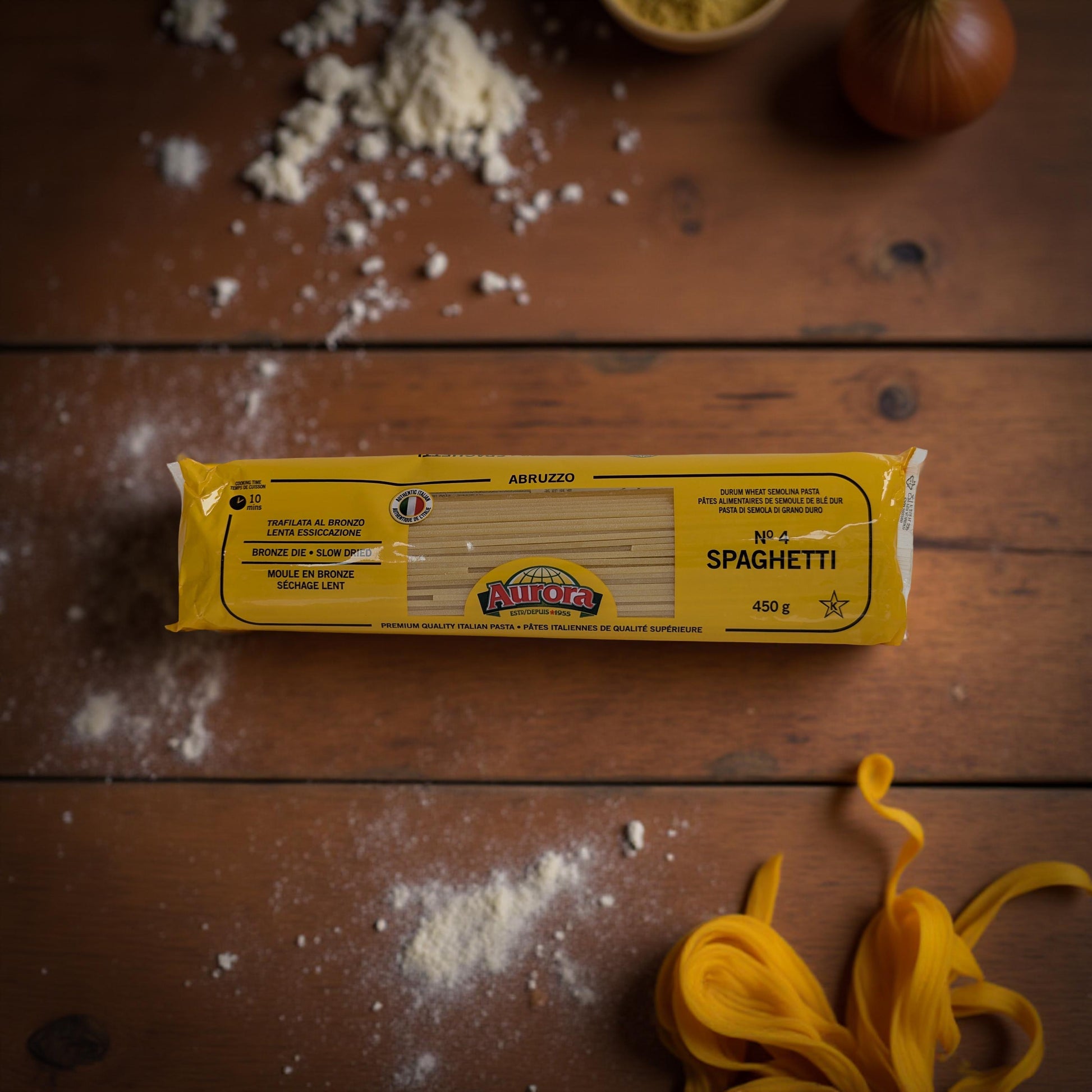 Alfio Spaghetti package on a wooden surface with uncooked spaghetti strands.