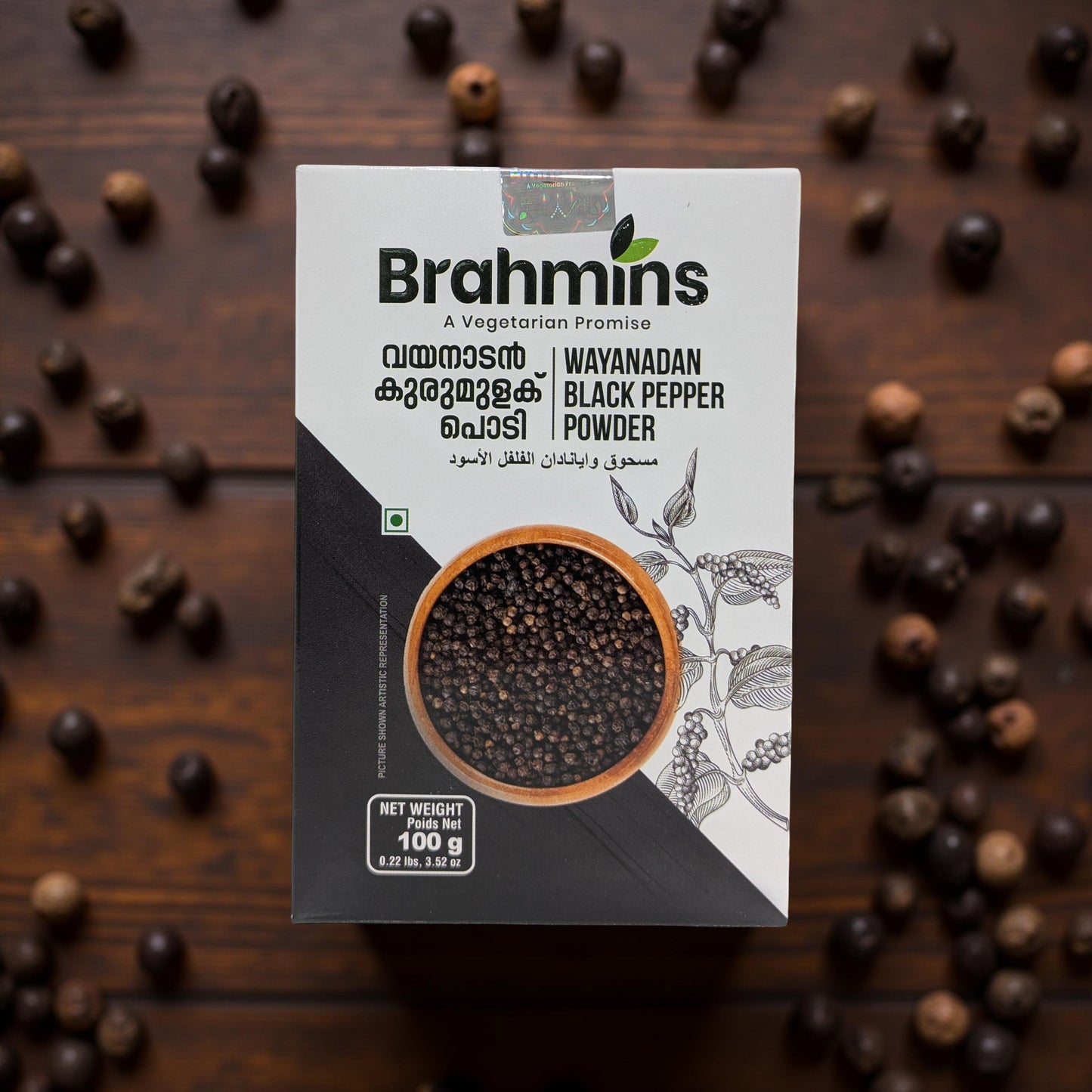 Brahmins Wayanadan Black Pepper Powder packaging on a wooden background with black pepper grains.