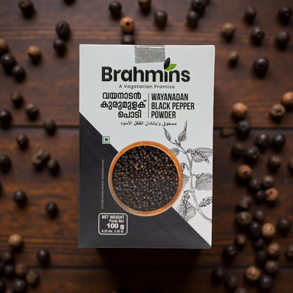 Brahmins Wayanadan Black Pepper Powder packaging on a wooden background with black pepper grains.