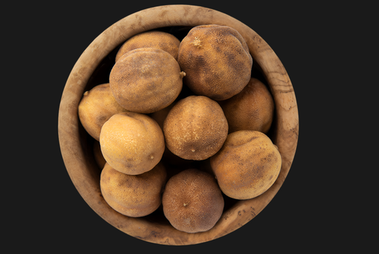 Wooden bowl filled with brown potatoes on a black background