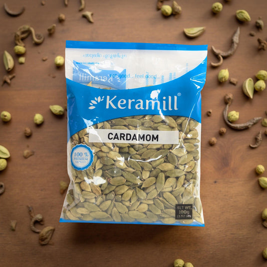 Keramill cardamom package on a wooden surface with scattered cardamom pods.