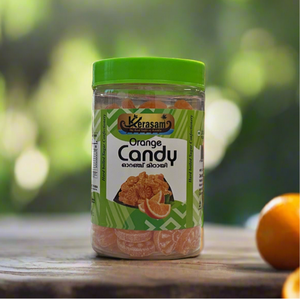 Jar of orange candy with a green lid on a wooden surface, blurred green background